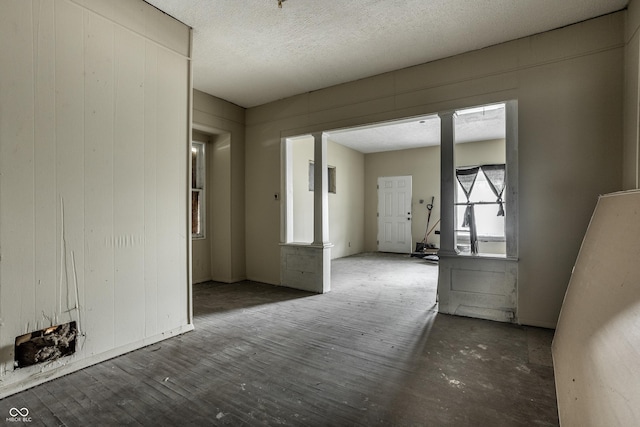 spare room with ornate columns, wood-type flooring, a textured ceiling, and wood walls