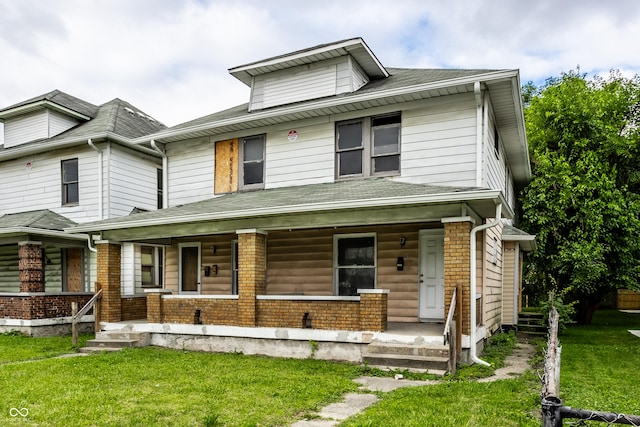 american foursquare style home featuring covered porch, a front lawn, and brick siding