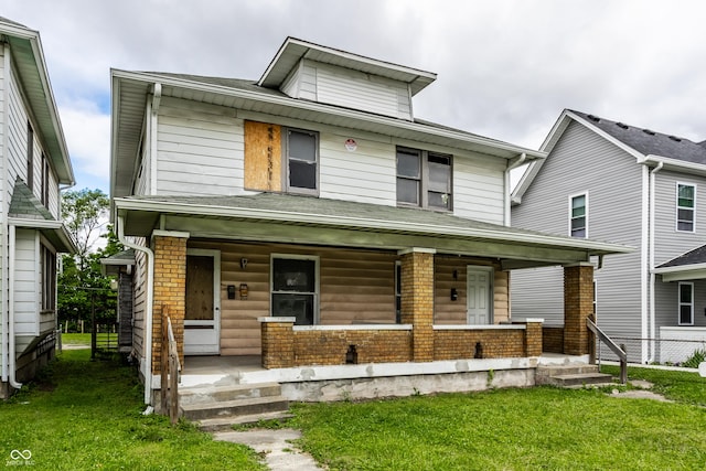 traditional style home with covered porch, fence, and a front lawn