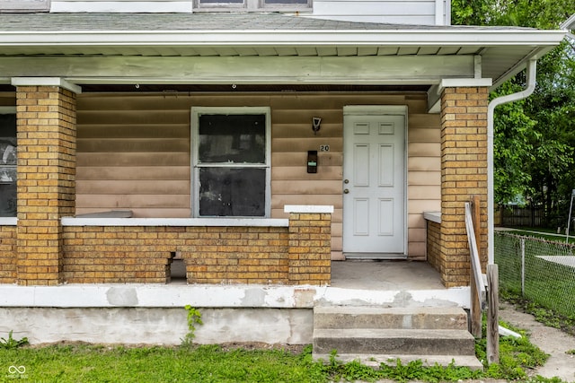 entrance to property with brick siding and fence