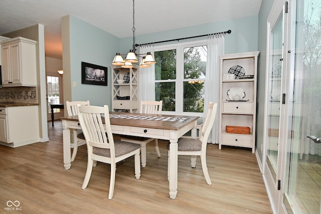 dining space with light wood-type flooring and an inviting chandelier