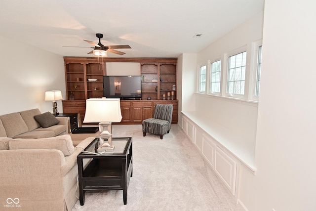 living area with light carpet, ceiling fan, visible vents, and built in features