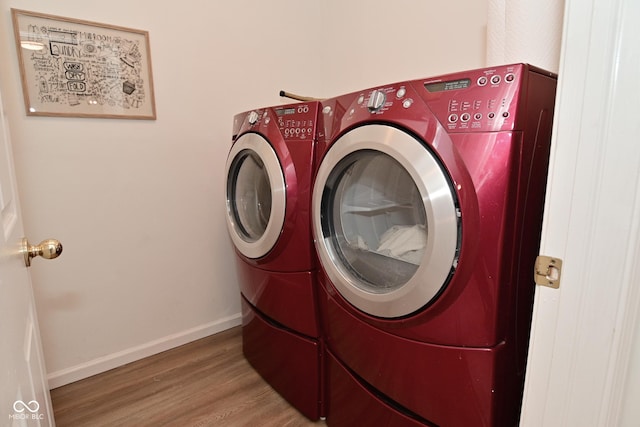 laundry room featuring laundry area, independent washer and dryer, baseboards, and wood finished floors