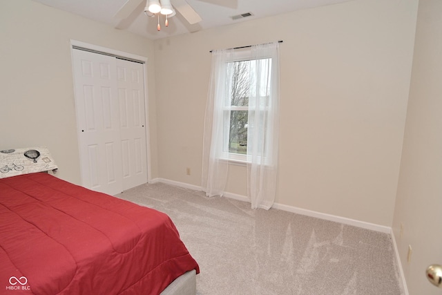 carpeted bedroom featuring a ceiling fan, baseboards, visible vents, and a closet