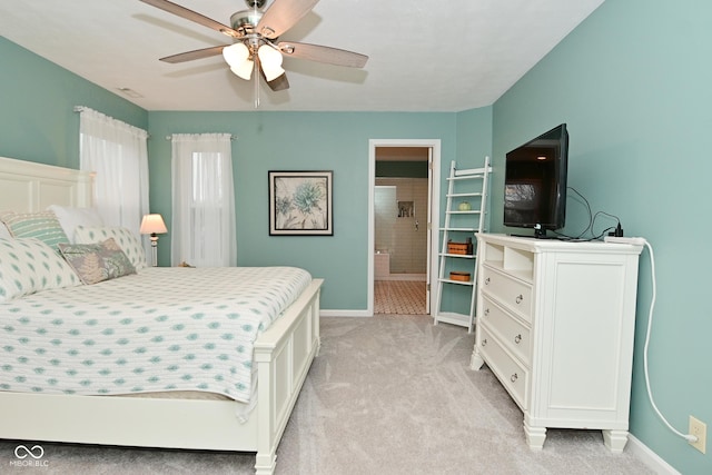 bedroom with a ceiling fan, light colored carpet, baseboards, and ensuite bathroom