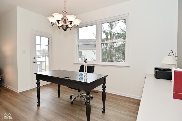 home office featuring light wood-style flooring, baseboards, and a notable chandelier