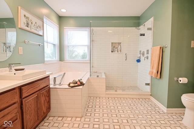 bathroom featuring a stall shower, baseboards, toilet, a garden tub, and vanity