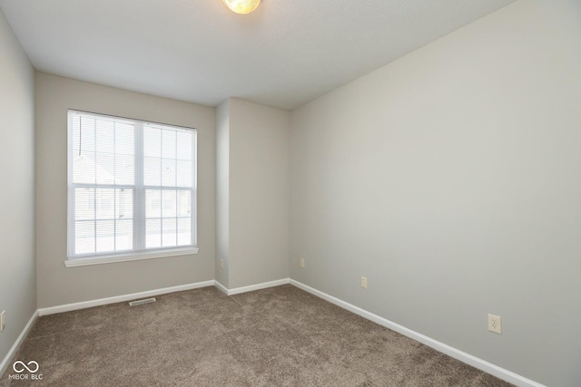 carpeted spare room with visible vents and baseboards