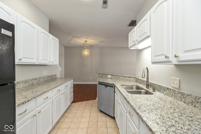 kitchen with stainless steel dishwasher, freestanding refrigerator, white cabinets, light tile patterned flooring, and a sink