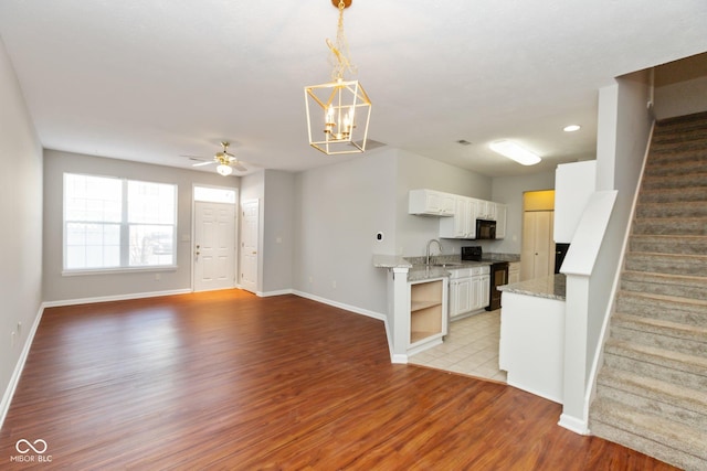 kitchen with range with electric stovetop, light wood-style flooring, white cabinets, a sink, and black microwave