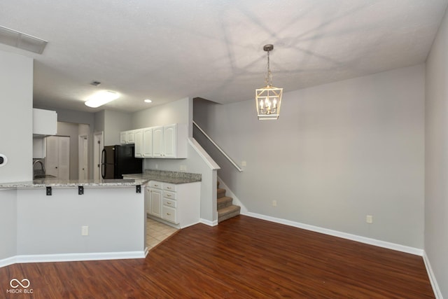 kitchen featuring a peninsula, a sink, visible vents, white cabinetry, and freestanding refrigerator