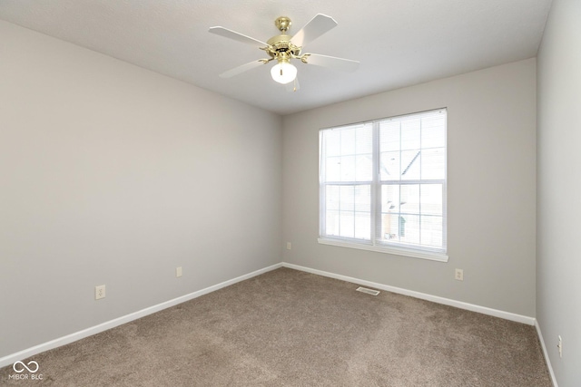 carpeted spare room featuring visible vents, baseboards, and a ceiling fan