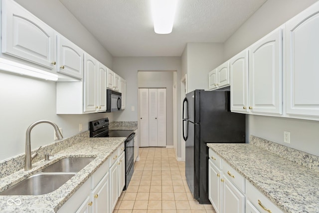 kitchen with white cabinetry, a sink, black appliances, and light stone countertops