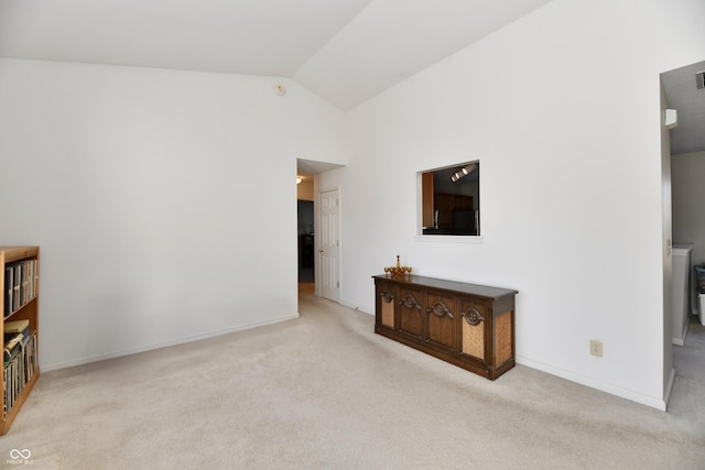 unfurnished living room with carpet flooring, baseboards, and lofted ceiling