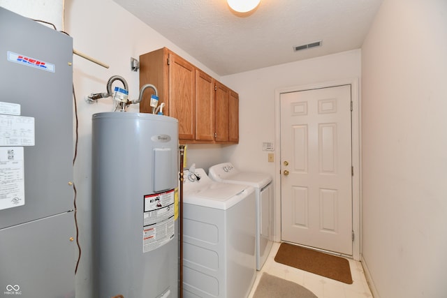 laundry area featuring visible vents, washer and clothes dryer, a textured ceiling, water heater, and cabinet space