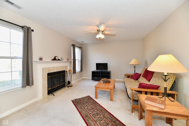 living room featuring baseboards, visible vents, a fireplace, ceiling fan, and light carpet