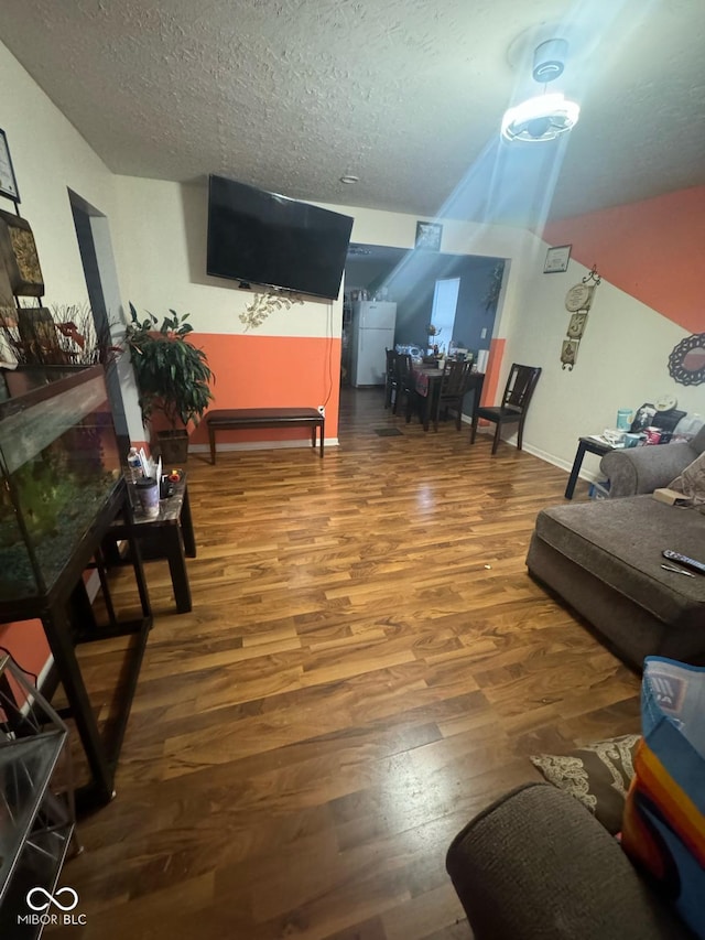living area with a textured ceiling, baseboards, and wood finished floors