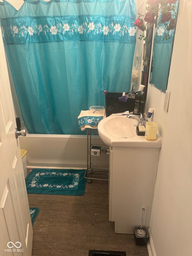 bathroom with wood finished floors, a sink, and shower / tub combo with curtain