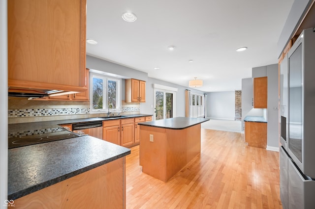 kitchen with a kitchen island, a sink, stainless steel dishwasher, stovetop, and dark countertops