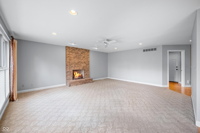 unfurnished living room with carpet, a brick fireplace, visible vents, and recessed lighting