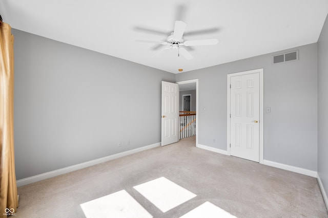 unfurnished bedroom featuring light colored carpet, visible vents, ceiling fan, and baseboards