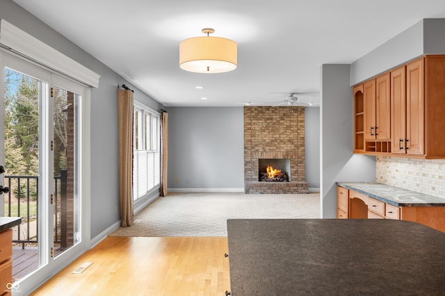 interior space with a brick fireplace, plenty of natural light, backsplash, and baseboards