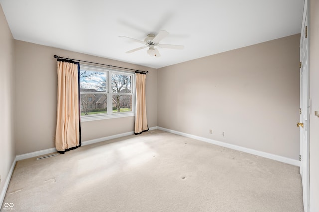 empty room with light colored carpet, a ceiling fan, and baseboards