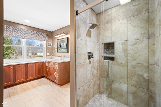 full bath featuring tiled shower and vanity