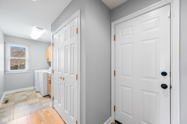 clothes washing area featuring cabinet space, visible vents, light wood-style floors, washer and dryer, and baseboards