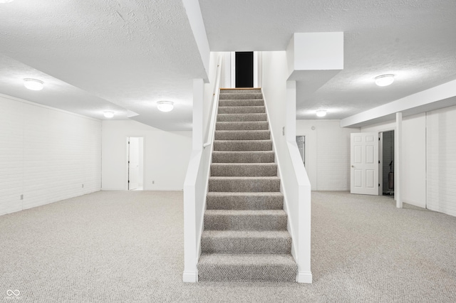 stairway featuring a textured ceiling and carpet