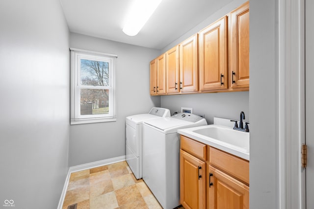 clothes washing area with a sink, washing machine and dryer, cabinet space, and baseboards