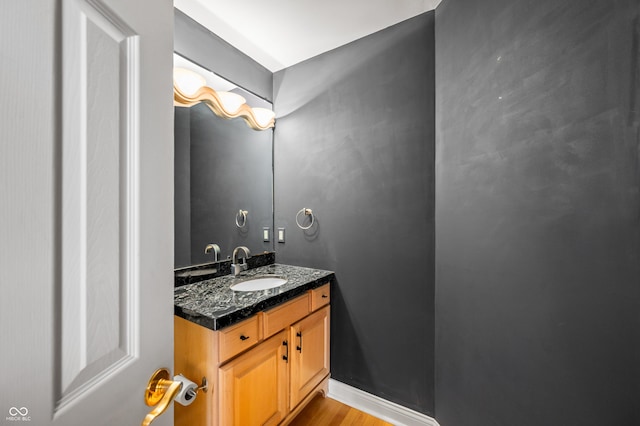 bathroom featuring baseboards, wood finished floors, and vanity