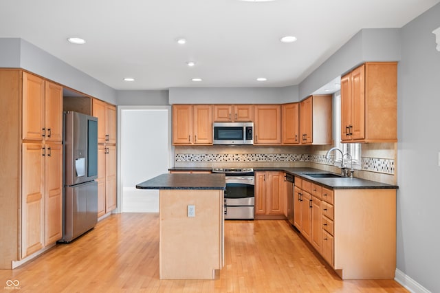 kitchen featuring dark countertops, stainless steel appliances, a sink, and a center island