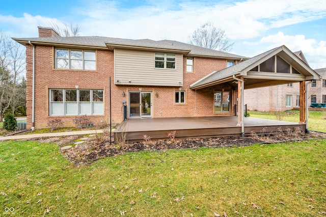 rear view of property with a deck, brick siding, a yard, and a chimney