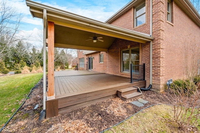 wooden terrace featuring ceiling fan and a lawn