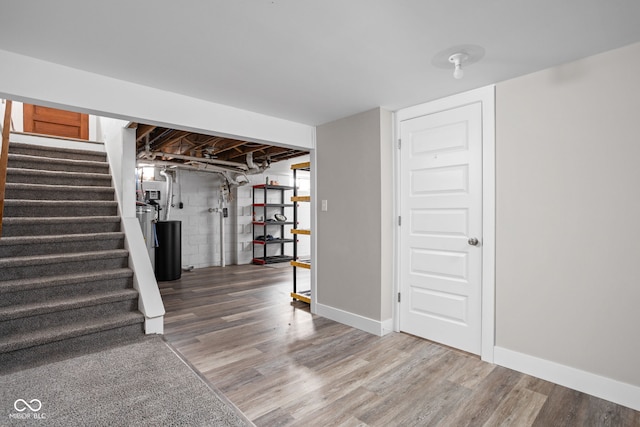 unfinished below grade area with stairs, baseboards, and wood finished floors