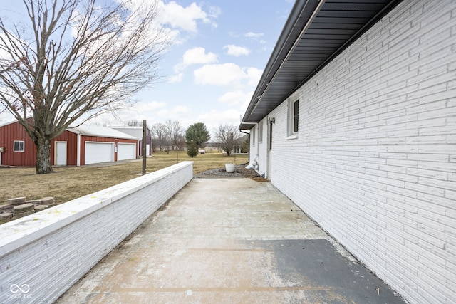 view of property exterior featuring a garage, brick siding, and an outdoor structure