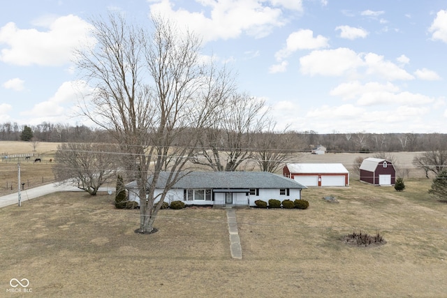 ranch-style house featuring a garage, an outbuilding, a rural view, and fence