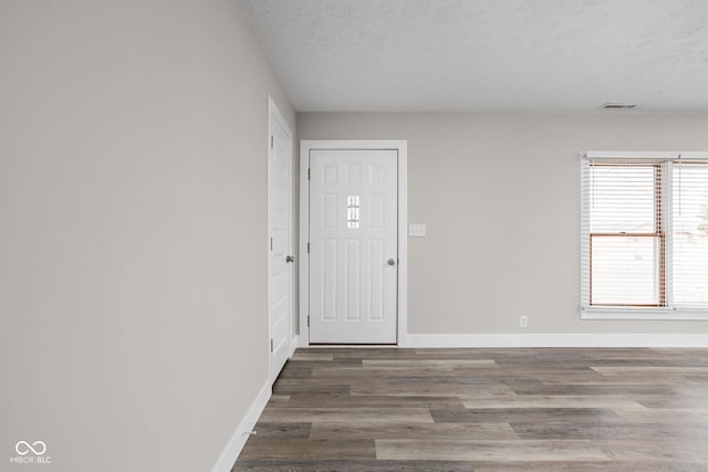 foyer with baseboards, a textured ceiling, visible vents, and wood finished floors