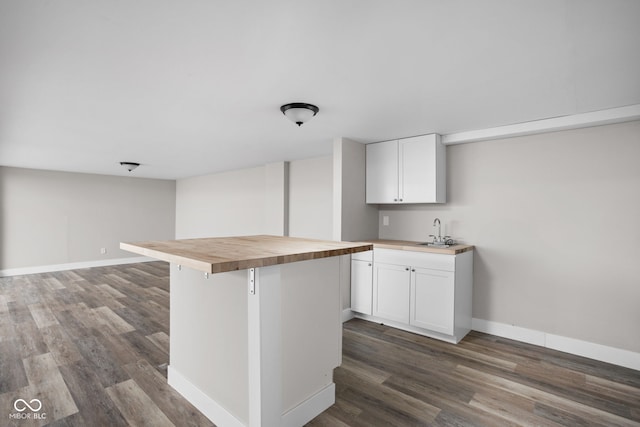 kitchen with dark wood-style floors, butcher block countertops, baseboards, and white cabinets