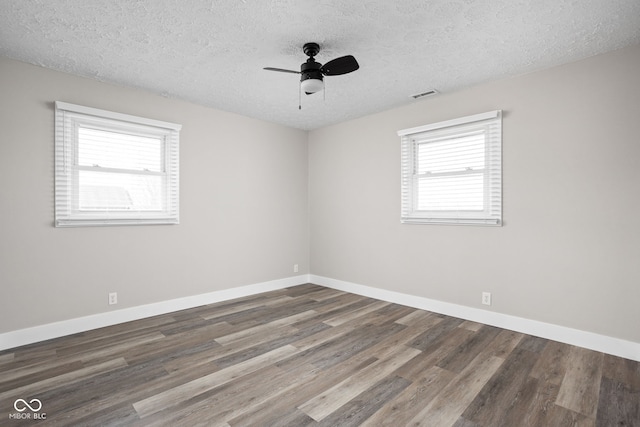 spare room with visible vents, ceiling fan, a textured ceiling, wood finished floors, and baseboards