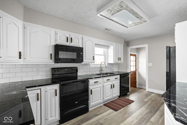 kitchen with dark countertops, decorative backsplash, white cabinets, a sink, and black appliances