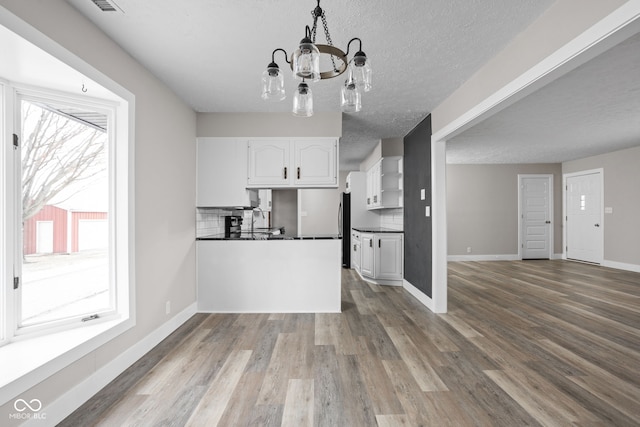 kitchen with dark countertops, wood finished floors, freestanding refrigerator, and white cabinets