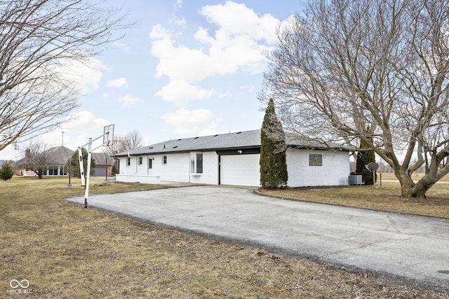 view of front of property featuring central AC unit, driveway, a front lawn, and an attached garage