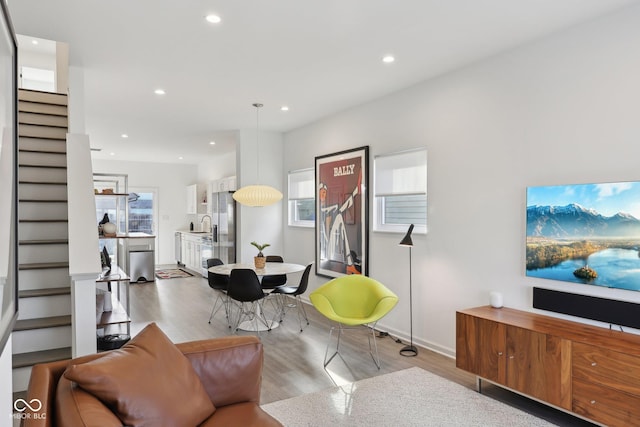 living room with a wealth of natural light, stairway, recessed lighting, and wood finished floors