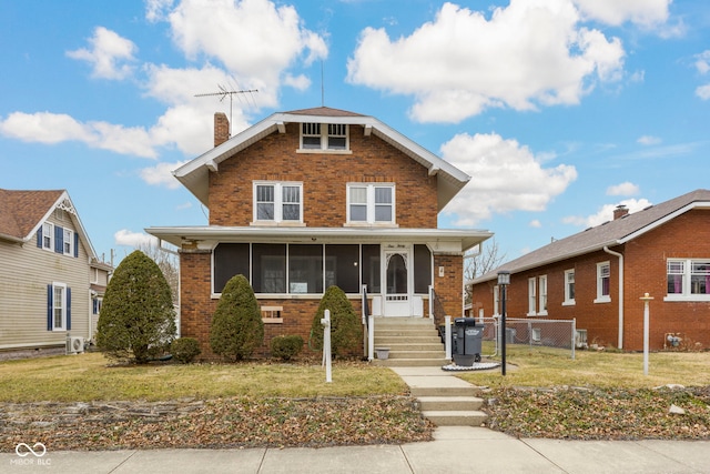 view of front of home featuring brick siding, fence, a sunroom, a front lawn, and a chimney