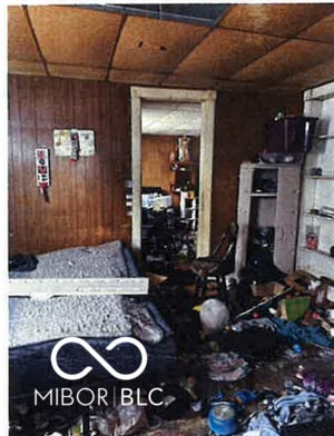 bedroom featuring a drop ceiling and wood walls