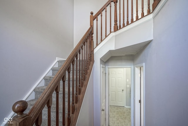 stairway featuring tile patterned floors, baseboards, and a high ceiling