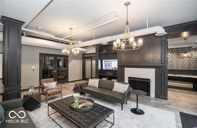 living area featuring a notable chandelier, a fireplace, and light wood-style floors