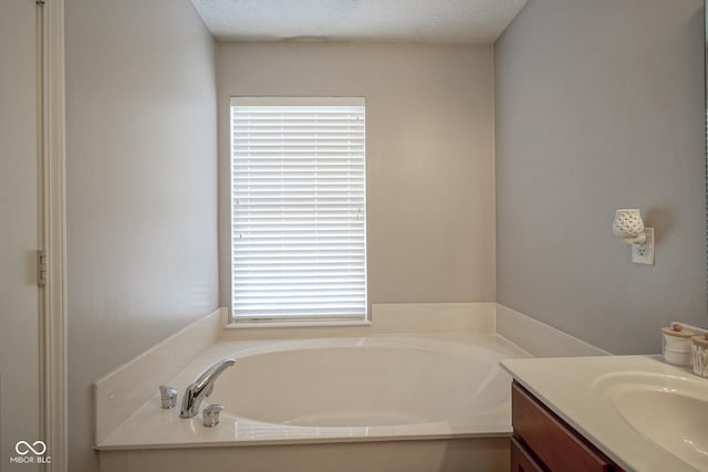 full bathroom with vanity, a garden tub, and a textured ceiling